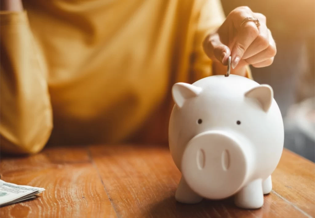 woman putting coins in piggy bank Rebates for hearing aids woman putting coins in piggy bank Rebates for hearing aids
